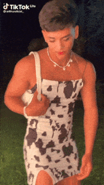 a man in a cow print dress is holding a white purse .