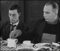 a black and white photo of two men sitting at a table with food . one of the men is pouring sugar into a cup .