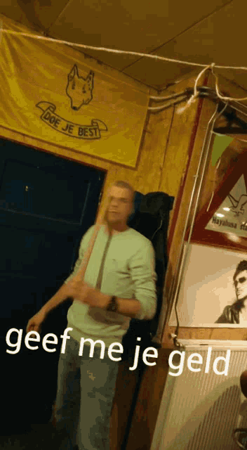 a man stands in front of a yellow banner that says ' doe je best '