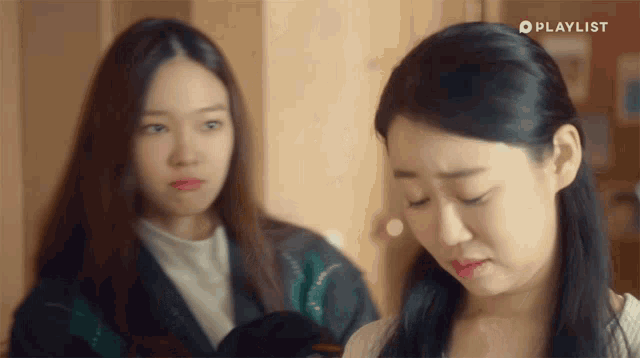 two women are standing next to each other with a playlist logo on the bottom right