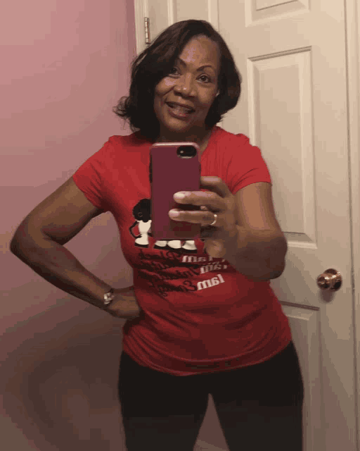 a woman in a red shirt takes a selfie in front of a mirror