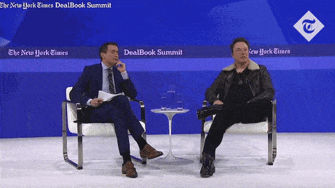 two men sit in front of a sign that says dealbook summit