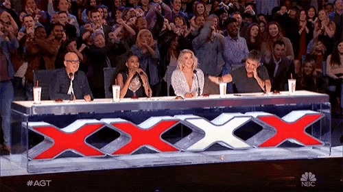 a group of people are sitting at a table with a large red x on it