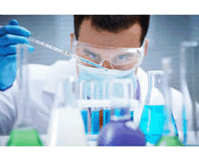 a scientist wearing a mask and goggles is pouring liquid into a beaker .