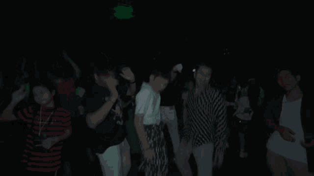 a group of people are dancing in a dark room and one of them is wearing a shirt that says r4 on it