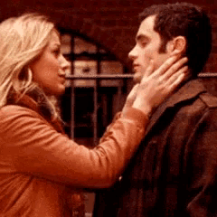 a woman is touching a man 's face while standing next to him .
