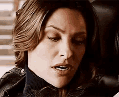 a close up of a woman 's face with a turtleneck and a leather jacket