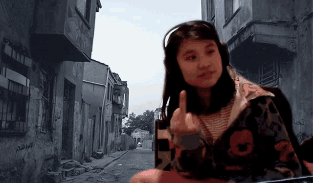 a girl wearing headphones giving the middle finger in front of a street