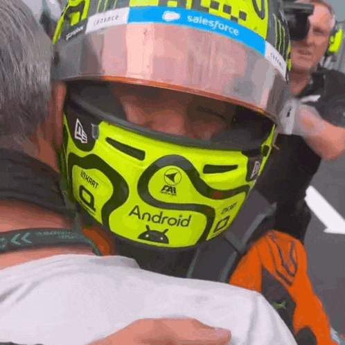 a man wearing a helmet that says android is hugging another man