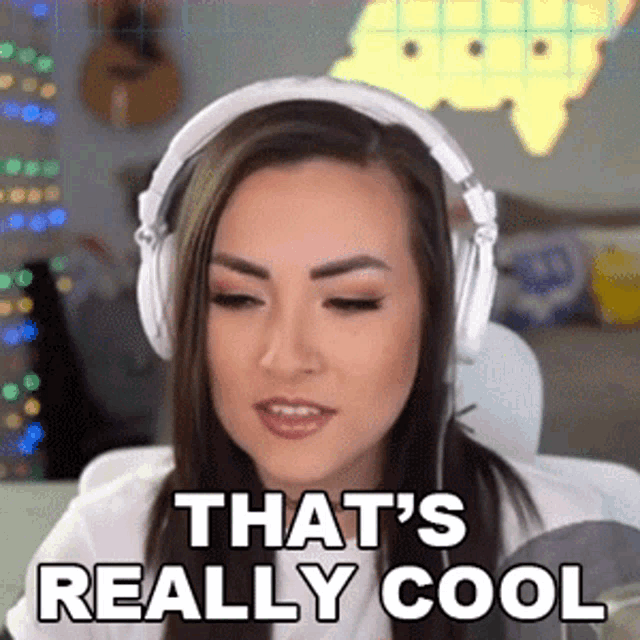 a woman wearing headphones says that 's really cool while sitting at a desk .