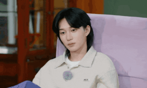 a young man is sitting in a purple chair wearing a white sweater that says nike