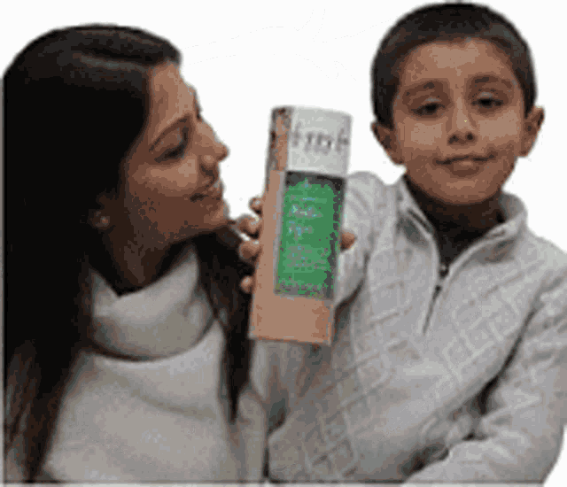 a woman is holding a child who is holding a cardboard tube with a green label on it .