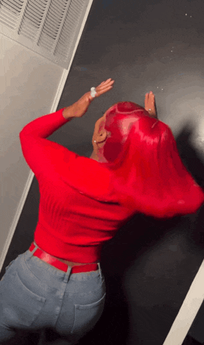 a woman with red hair is wearing a red sweater and blue jeans