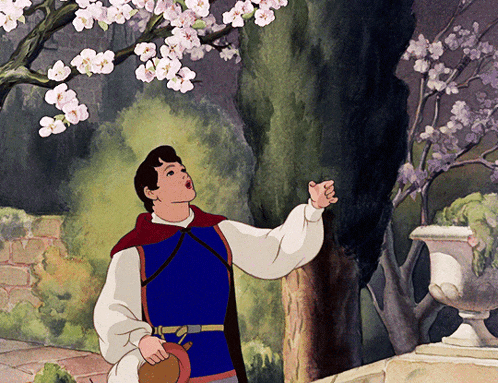 a man in a blue vest is looking up at a tree