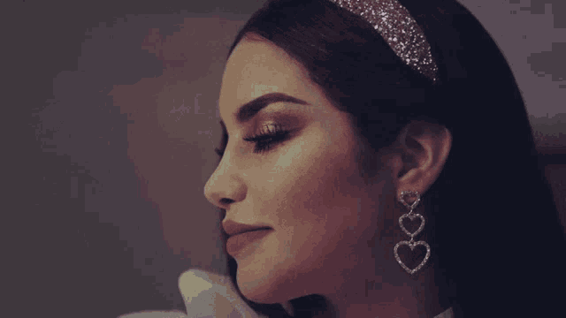a woman wearing heart shaped earrings and a headband with rhinestones