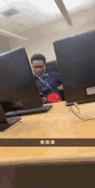 a man wearing headphones is sitting at a desk in front of two computer monitors