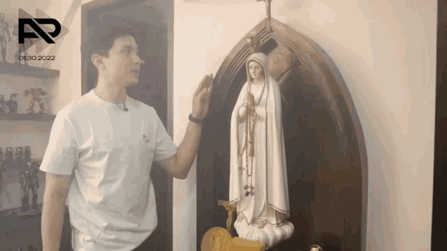 a man in a white shirt stands in front of a statue of a woman with the year 2022 on the bottom left