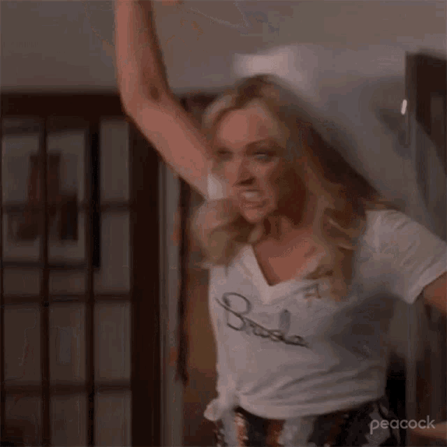 a woman wearing a white t-shirt and a veil is dancing in a room .