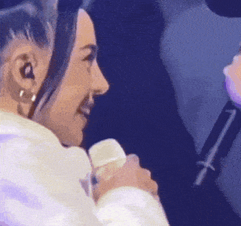a woman is holding a microphone in her hand and smiling while another woman sings into it .