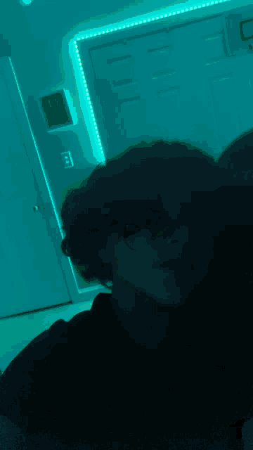 a person standing in a dark room with a blue light on the wall