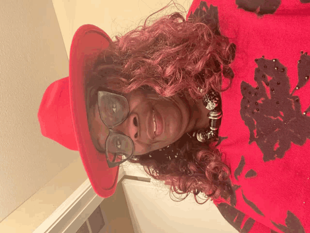 a woman wearing glasses and a red hat is smiling