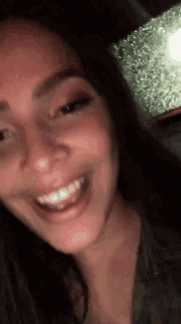 a close up of a woman 's face smiling and looking at the camera