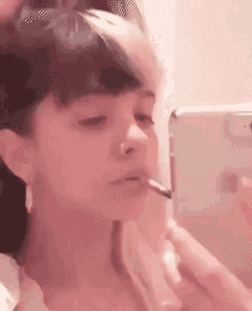 a woman is smoking a cigarette in front of her phone .