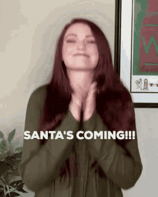 a woman with red hair is clapping her hands and saying santa 's coming !