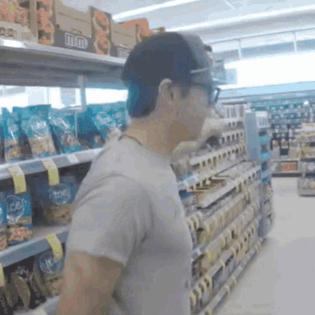 a man standing in a grocery store aisle with m & m 's on the shelves