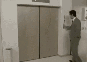 a man in a suit and tie is standing in front of an elevator with the doors open .