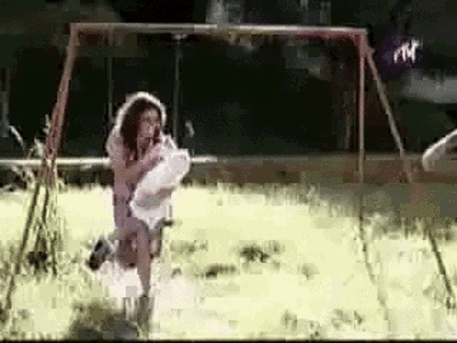 a woman is holding a child on a swing in a playground .