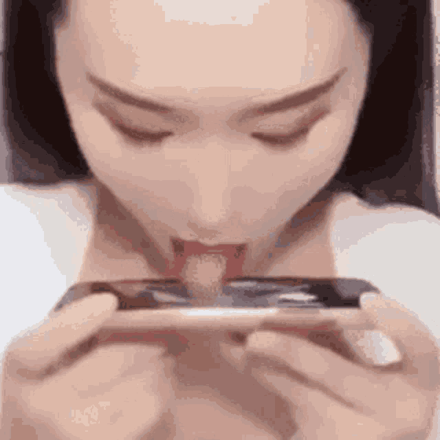 a woman is playing a game on her phone with her tongue out .