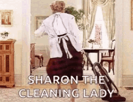 a woman in an apron is using a vacuum cleaner to clean a living room .