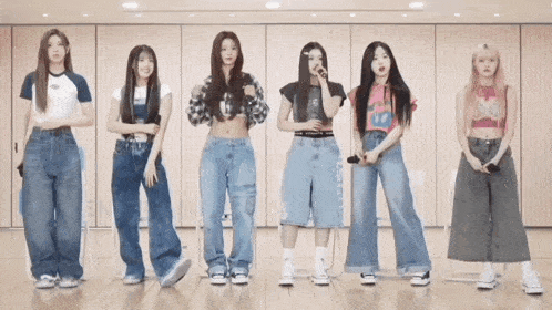 a group of girls are standing in a row wearing jeans
