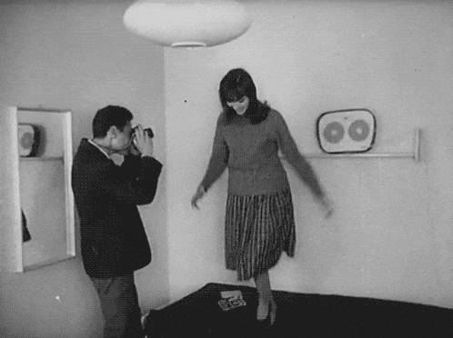 a man takes a picture of a woman in a room