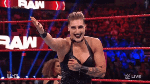 a woman in a black dress is standing in a wrestling ring with the word raw behind her