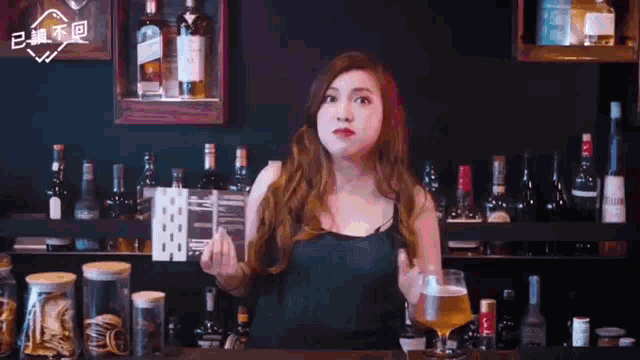 a woman is standing in front of a bar holding a glass of beer and playing cards
