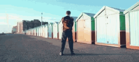 a man standing in front of a row of colorful beach huts