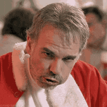 a man with a beard is wearing a santa claus outfit and making a funny face .
