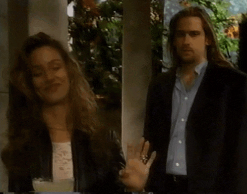 a man in a suit and a woman in a leather jacket are standing next to each other
