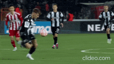 a soccer game is being played on a field with a sign that says neae in the background