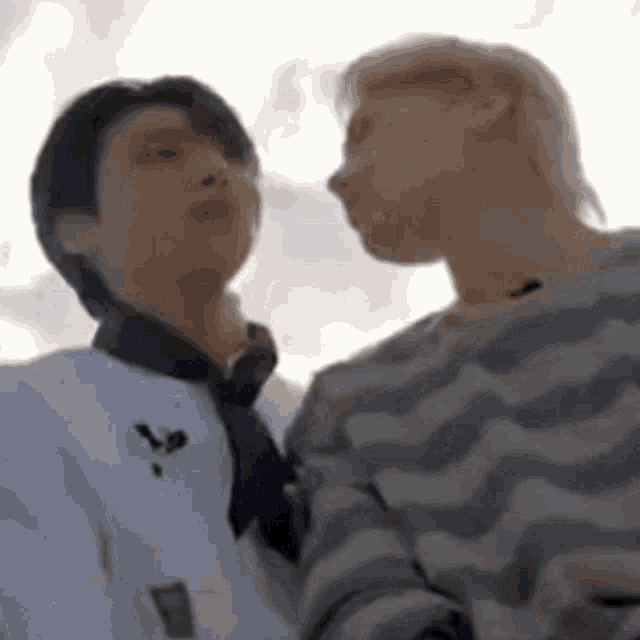 two men are standing next to each other and kissing each other .