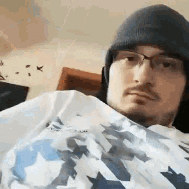 a man wearing a beanie and glasses is sitting in a room .