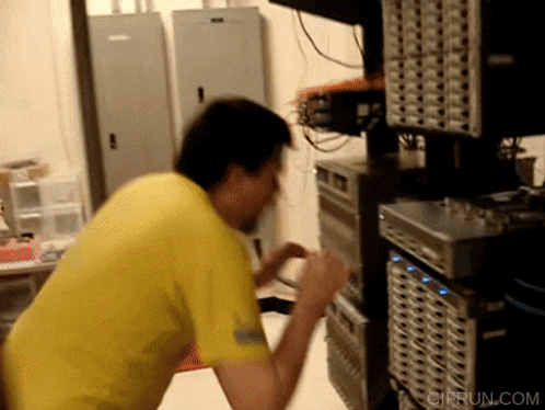 a man in a yellow shirt is standing in front of a server with a gifrun.com watermark