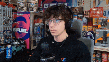 a man wearing headphones sits in front of a gfuel cooler