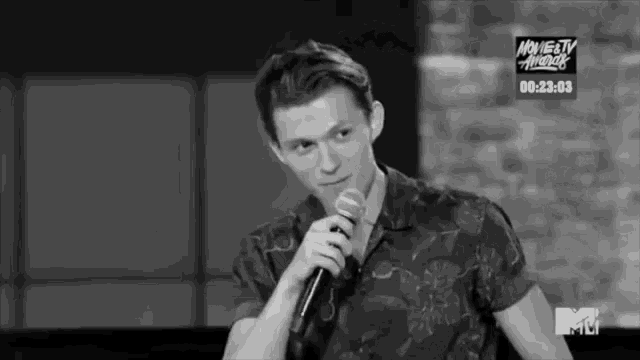 a man is holding a microphone in front of a tv screen that says mtv awards