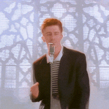 a man is singing into a microphone with his eyes closed