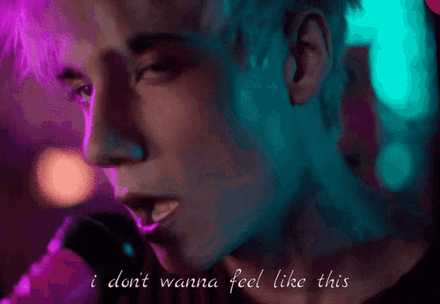a close up of a man singing into a microphone with the words i don t wanna feel like this below him