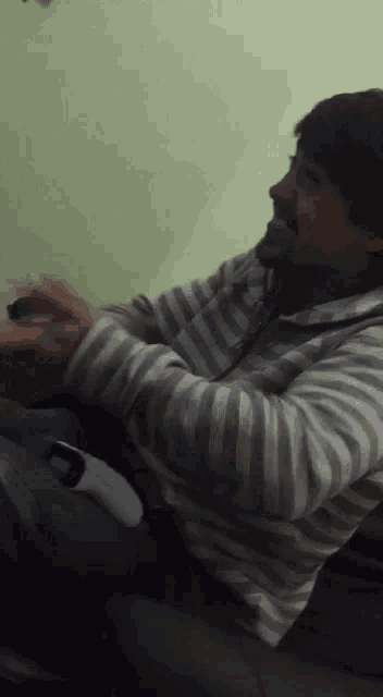 a man in a striped shirt is holding a controller