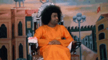 a man in an orange robe is sitting in a chair with the website www.radiosal.org displayed above him